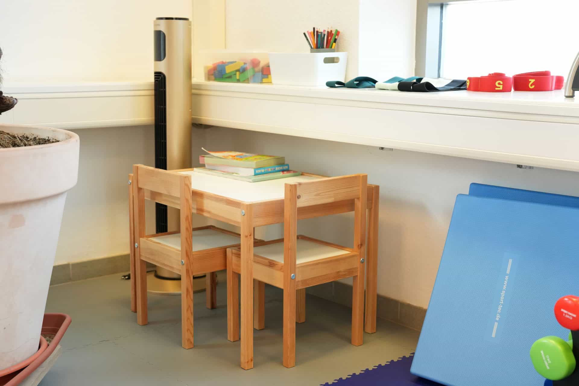 Kinderstuhl, Tisch, Bücher, Stifte und Spielzeug.