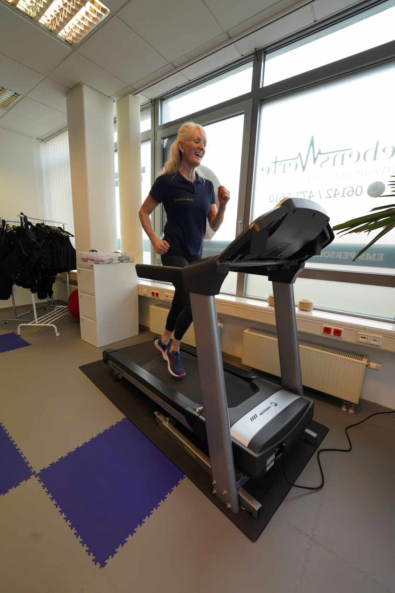 Person läuft auf Laufband im Fitnessstudio.