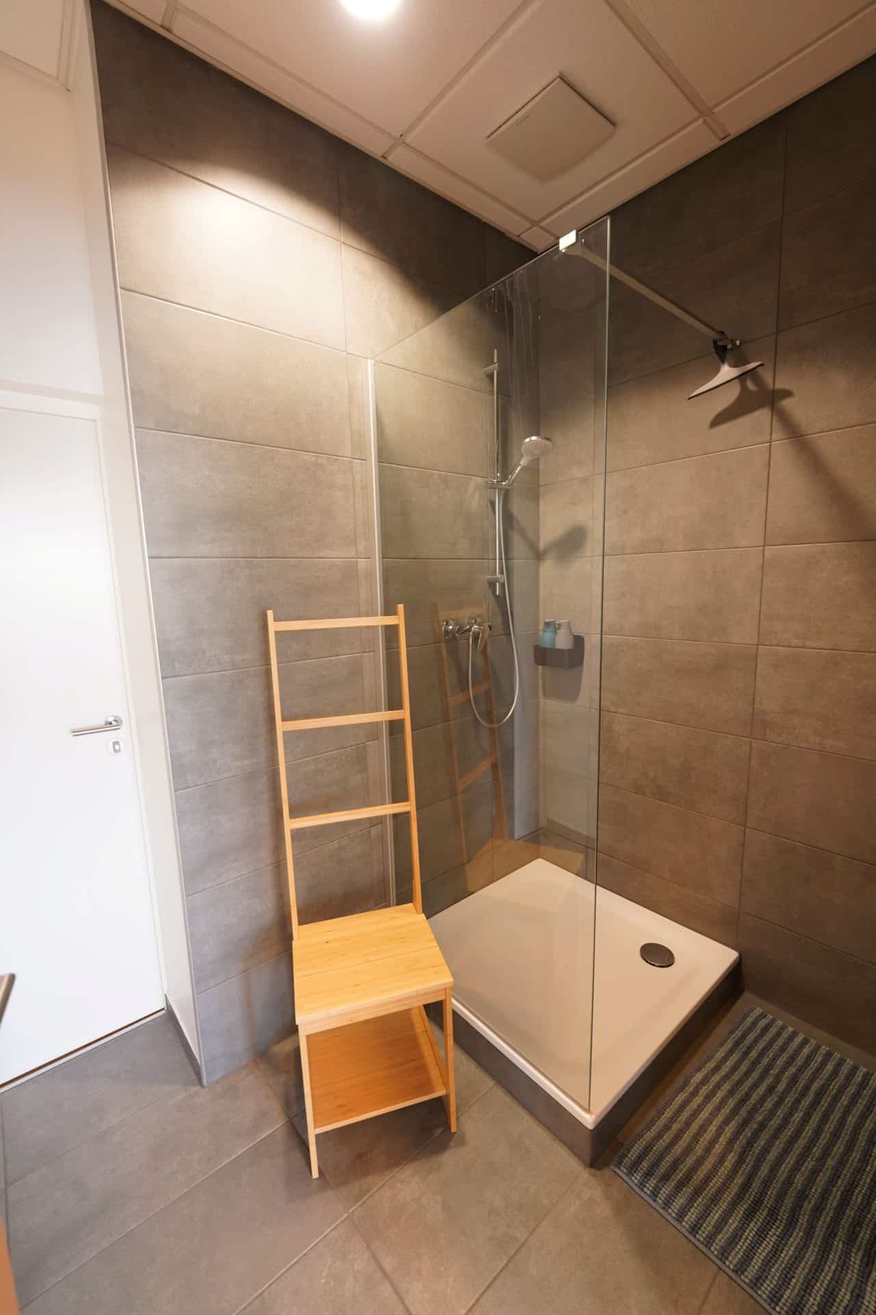 Moderne Dusche mit Holzstuhl im Badezimmer